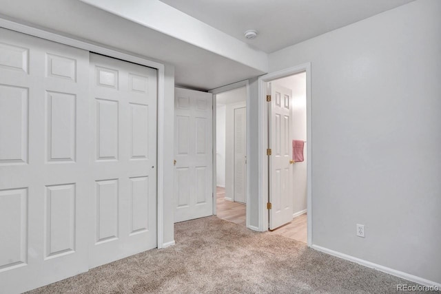 unfurnished bedroom with light carpet and a closet