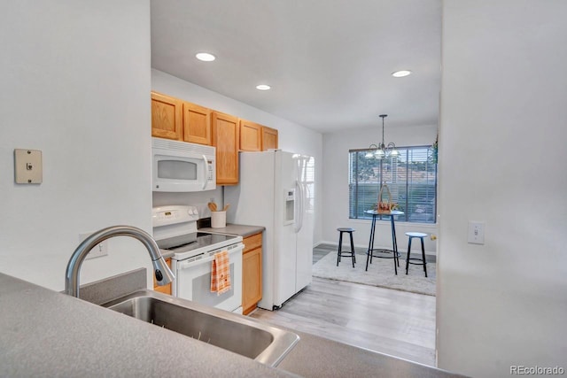 kitchen featuring sink, a notable chandelier, light hardwood / wood-style floors, decorative light fixtures, and white appliances