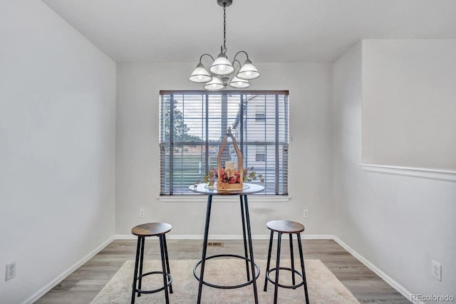 dining area featuring wood-type flooring and a chandelier