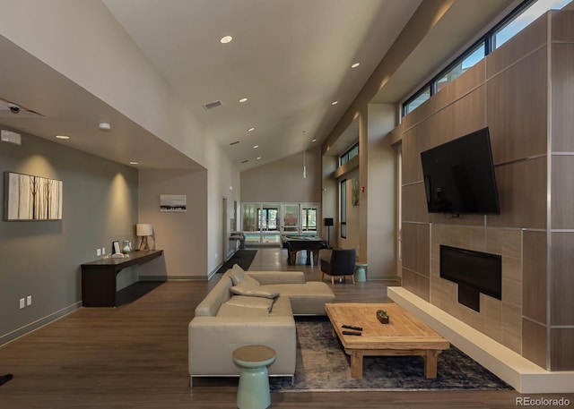 living room with a tiled fireplace, hardwood / wood-style floors, and high vaulted ceiling