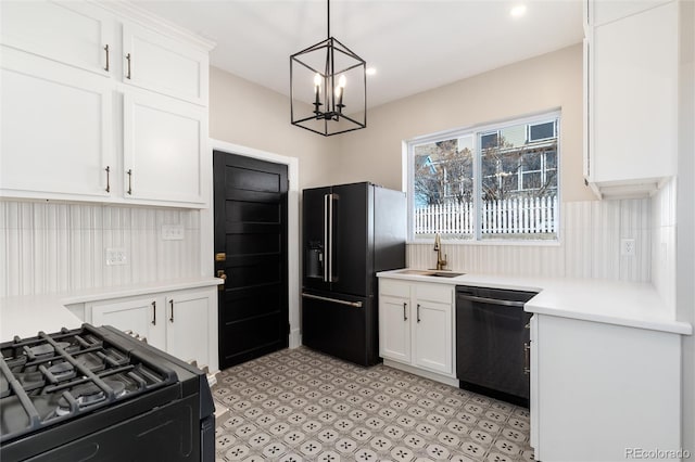 kitchen featuring pendant lighting, sink, white cabinetry, an inviting chandelier, and black appliances