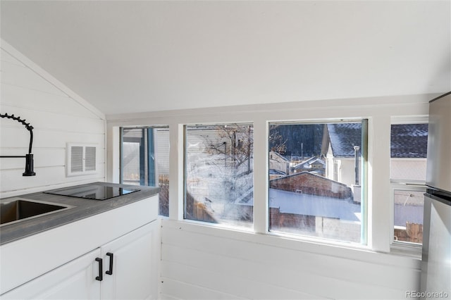 kitchen featuring white cabinetry, sink, vaulted ceiling, and a healthy amount of sunlight