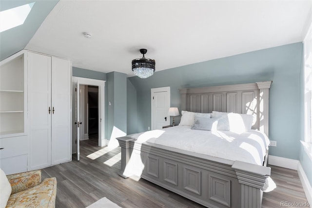 bedroom featuring a notable chandelier, dark hardwood / wood-style flooring, and a skylight