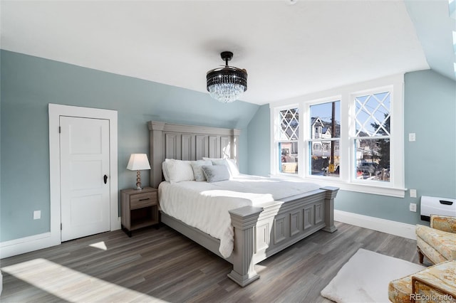 bedroom with lofted ceiling, dark wood-type flooring, and a chandelier