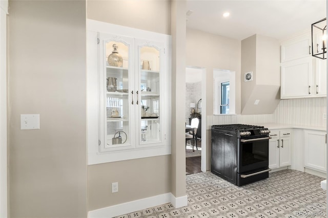 kitchen with black gas range, pendant lighting, and white cabinets