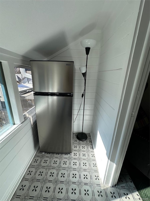 room details featuring stainless steel fridge and wood walls