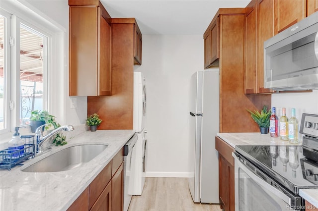 kitchen featuring sink, light stone countertops, light hardwood / wood-style floors, and appliances with stainless steel finishes