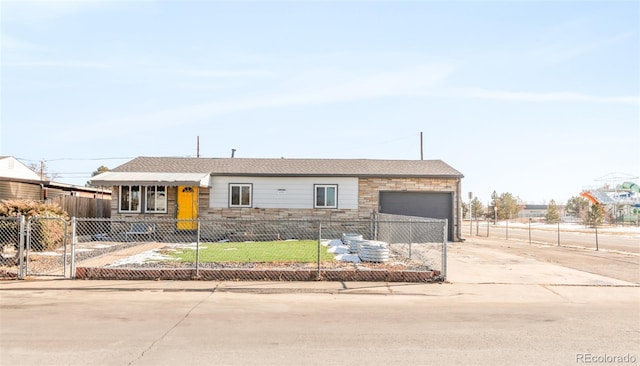 view of front of property with concrete driveway, stone siding, a garage, and a fenced front yard