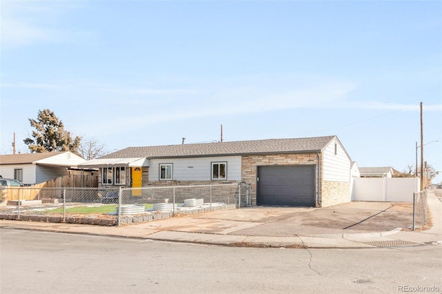 ranch-style home with a fenced front yard, concrete driveway, and a garage