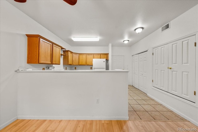 202 Lucca Dr, Evans, CO 80620 - kitchen featuring freestanding refrigerator, a peninsula, light countertops, ceiling fan, and baseboards