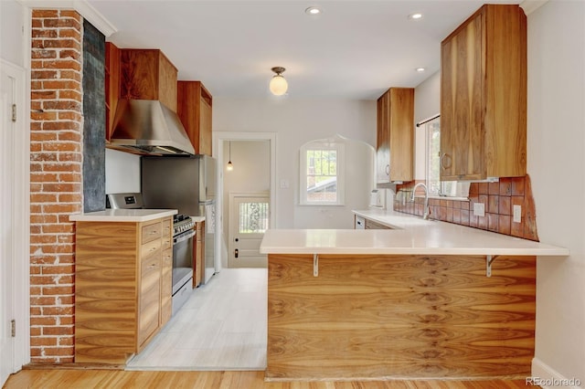 2636 N Glencoe St, Denver, CO 80207 - kitchen featuring range hood, range, light countertops, a peninsula, and brown cabinetry
