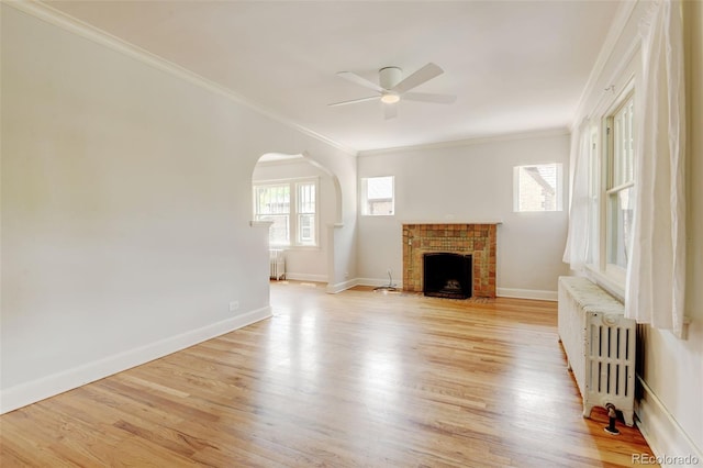 2636 N Glencoe St, Denver, CO 80207 - unfurnished living room featuring radiator, ceiling fan, arched walkways, light wood-style floors, and a fireplace