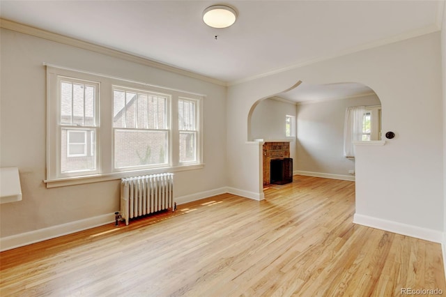 2636 N Glencoe St, Denver, CO 80207 - unfurnished living room with radiator, ornamental molding, wood finished floors, baseboards, and arched walkways