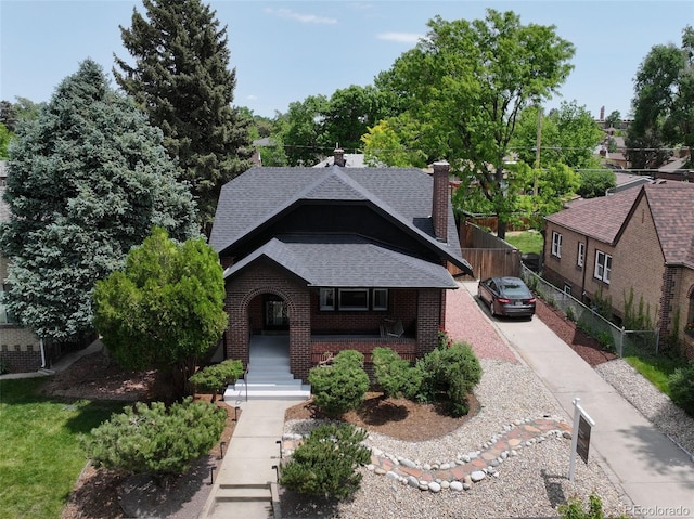 2636 N Glencoe St, Denver, CO 80207 - tudor home with a shingled roof, brick siding, a porch, and a chimney