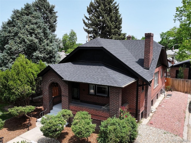 2636 N Glencoe St, Denver, CO 80207 - view of front facade with roof with shingles, a porch, a chimney, and brick siding