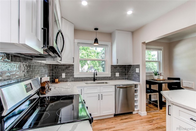 1969 Uinta St, Denver, CO 80220 - kitchen with appliances with stainless steel finishes, light stone countertops, white cabinets, decorative backsplash, and light wood finished floors