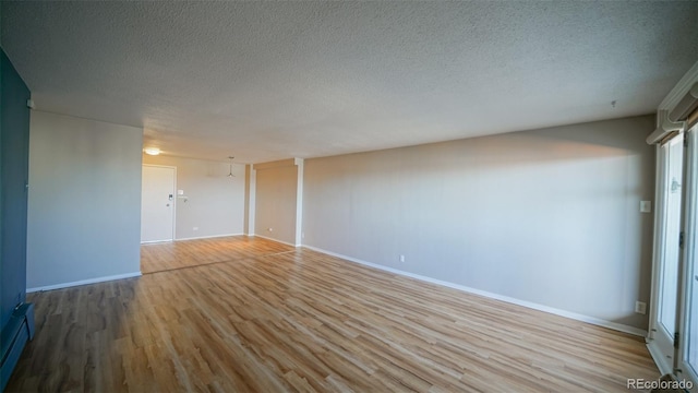 unfurnished room featuring a textured ceiling, light hardwood / wood-style flooring, and a baseboard heating unit