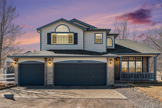 traditional-style home featuring a porch, concrete driveway, a shingled roof, and a garage