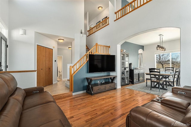 living area with baseboards, arched walkways, wood finished floors, stairs, and a high ceiling