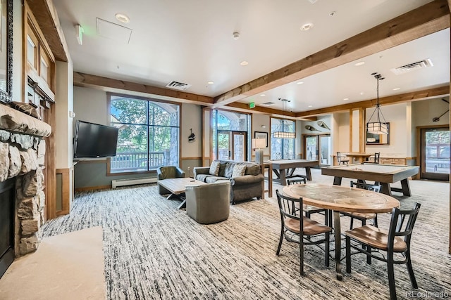 carpeted living room with beam ceiling, a stone fireplace, and baseboard heating