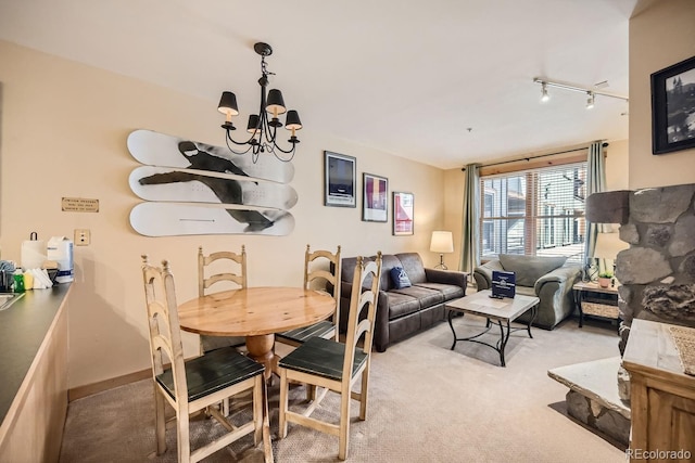 dining room featuring carpet, track lighting, and a notable chandelier