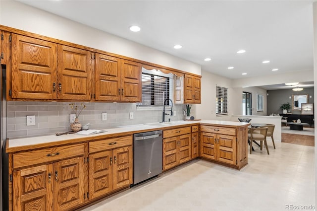 kitchen with dishwasher, a peninsula, light countertops, and brown cabinets