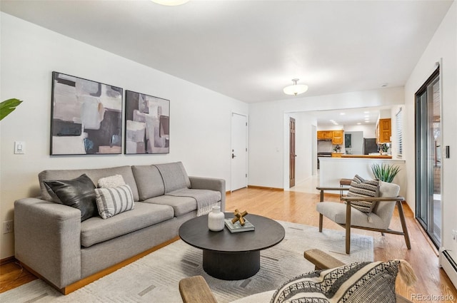 living area featuring baseboards, baseboard heating, and light wood-style flooring