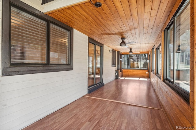 unfurnished sunroom with wood ceiling and a ceiling fan