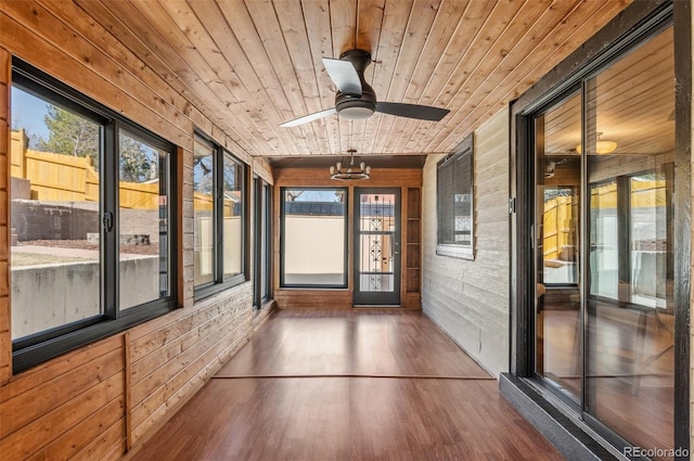 unfurnished sunroom with ceiling fan with notable chandelier, wood ceiling, and a healthy amount of sunlight