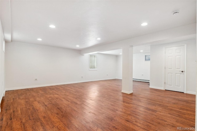 below grade area with baseboard heating, recessed lighting, baseboards, and wood finished floors