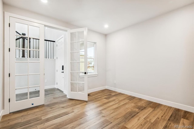 empty room featuring recessed lighting, baseboards, wood finished floors, and french doors