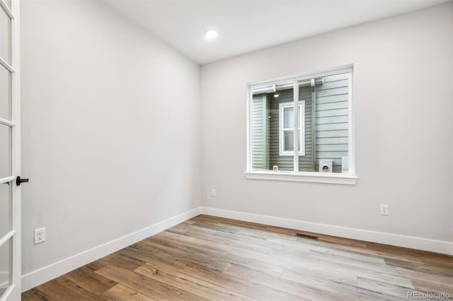 empty room featuring visible vents, baseboards, wood finished floors, and recessed lighting