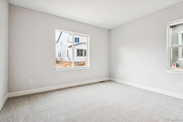 empty room with carpet floors, visible vents, and baseboards