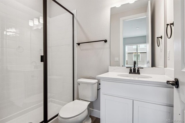 bathroom featuring toilet, a stall shower, and vanity