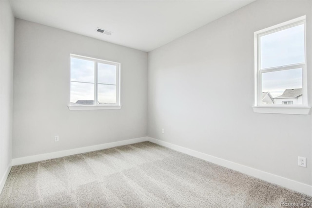 carpeted spare room with visible vents and baseboards