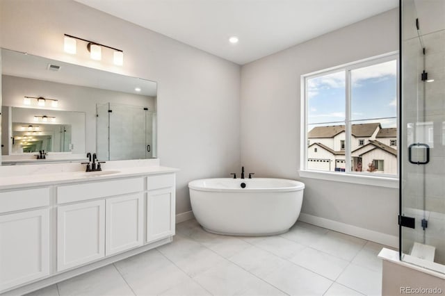 bathroom with visible vents, a freestanding bath, a shower stall, vanity, and baseboards