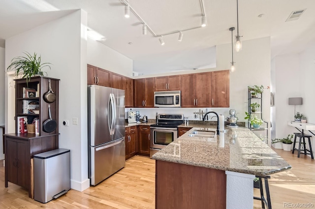 kitchen featuring visible vents, a sink, stainless steel appliances, a peninsula, and a breakfast bar area