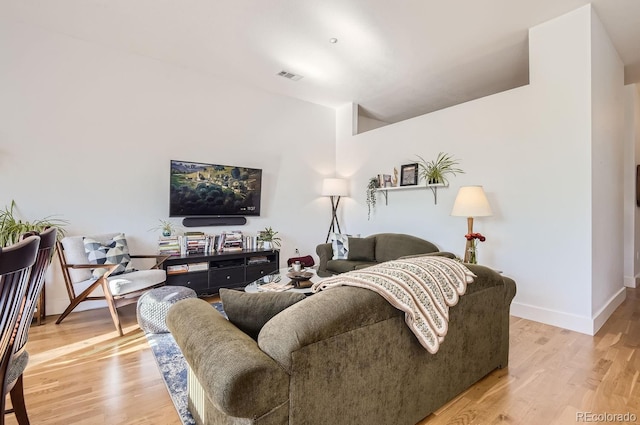 living room with baseboards, visible vents, and light wood finished floors