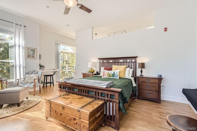 bedroom featuring rail lighting, wood finished floors, baseboards, and ceiling fan