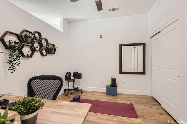 office featuring visible vents, ceiling fan, baseboards, light wood-style floors, and a textured ceiling