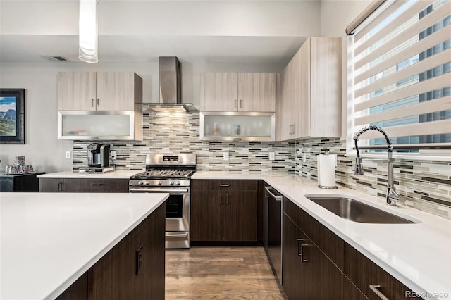 kitchen with stainless steel appliances, light countertops, visible vents, a sink, and wall chimney exhaust hood