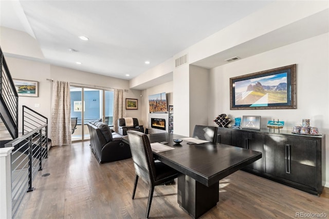 dining room featuring stairs, visible vents, wood finished floors, and a glass covered fireplace