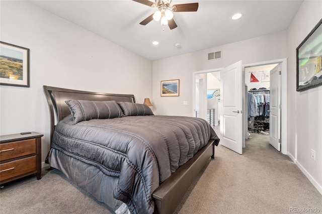 bedroom featuring a walk in closet, recessed lighting, visible vents, light carpet, and baseboards