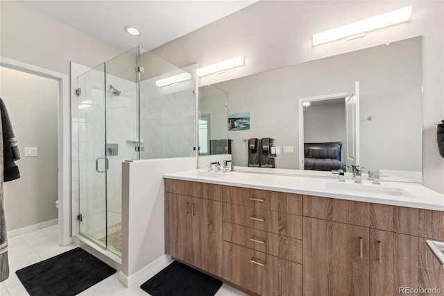 bathroom featuring connected bathroom, a sink, baseboards, double vanity, and a stall shower