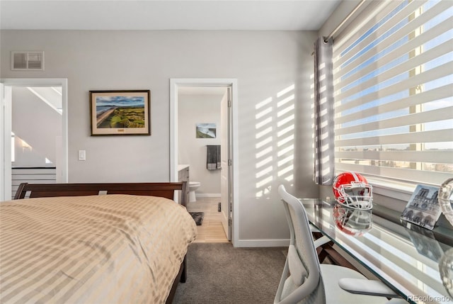 carpeted bedroom with visible vents, ensuite bath, and baseboards