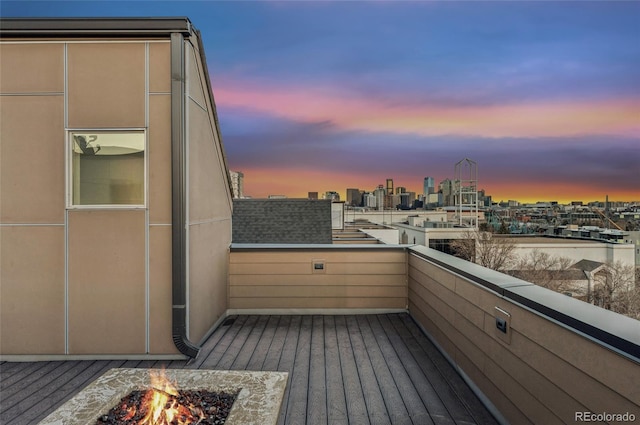 balcony at dusk with a view of city and an outdoor fire pit