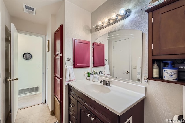 bathroom with tile patterned flooring, vanity, visible vents, and a textured wall