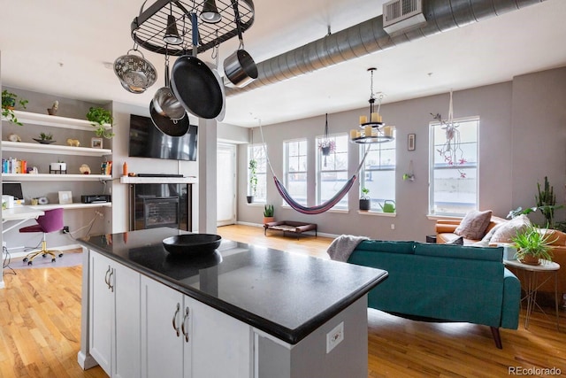 kitchen with dark countertops, light wood-type flooring, white cabinetry, and a center island