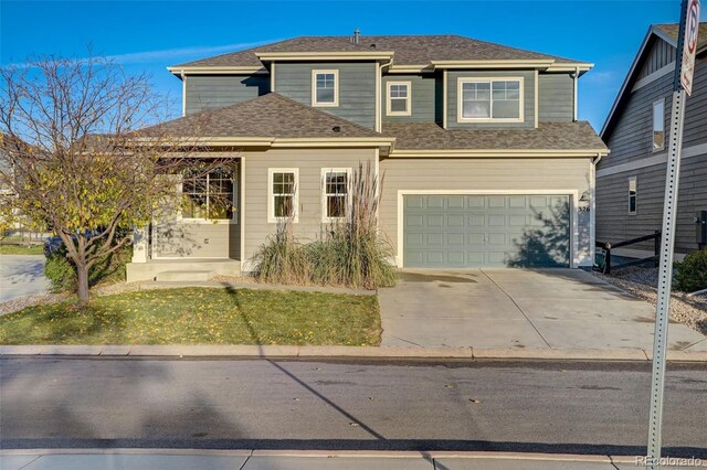 view of front facade with an attached garage, a shingled roof, and concrete driveway