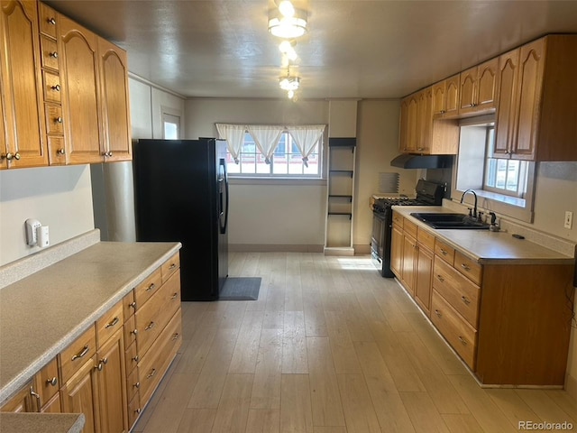 kitchen with sink, black appliances, and light hardwood / wood-style floors